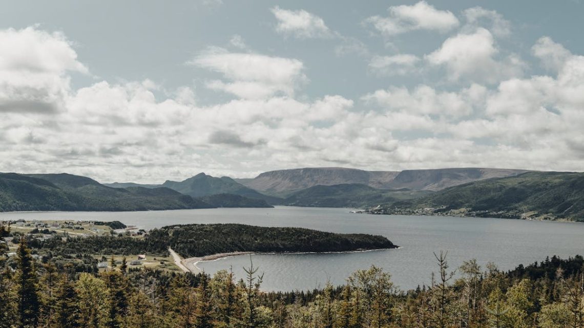 Vibrant summer landscape of Norris Point, NL with lush forests and tranquil lake.